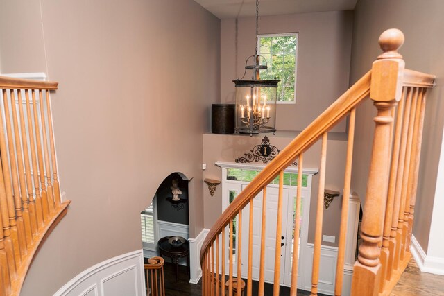 406 Elderberry Ln, Streamwood, IL 60107 - stairway featuring a chandelier, wood finished floors, a decorative wall, and a wainscoted wall