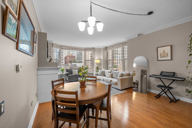25 E Superior St Unit 903, Chicago, IL 60611 - dining space featuring crown molding, wood finished floors, a chandelier, arched walkways, and baseboards
