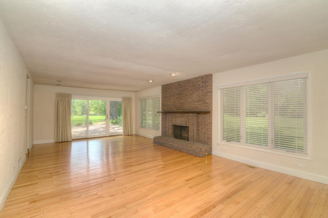 6N002 Laurel Dr, Medinah, IL 60157 - unfurnished living room featuring baseboards, light wood-style floors, and a brick fireplace