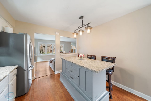 5317 Benton Ave, Downers Grove, IL 60515 - kitchen featuring freestanding refrigerator, a kitchen breakfast bar, hardwood / wood-style flooring, and baseboards