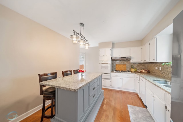 5317 Benton Ave, Downers Grove, IL 60515 - kitchen featuring white oven, tasteful backsplash, white cabinets, under cabinet range hood, and light stone countertops