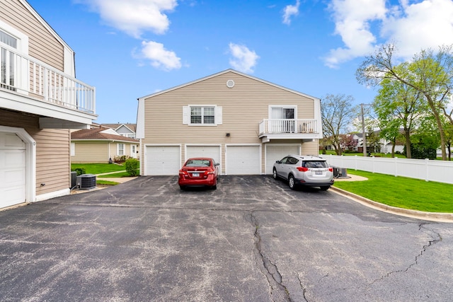 1585 Woodcutter Ln Unit D, Wheaton, IL 60189 - view of side of property featuring asphalt driveway, a garage, central AC unit, a residential view, and a balcony