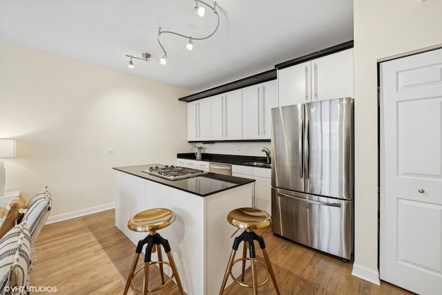 3721 N Sheffield Ave Unit B2, Chicago, IL 60613 - kitchen featuring appliances with stainless steel finishes, dark countertops, white cabinetry, light wood-style floors, and a kitchen island