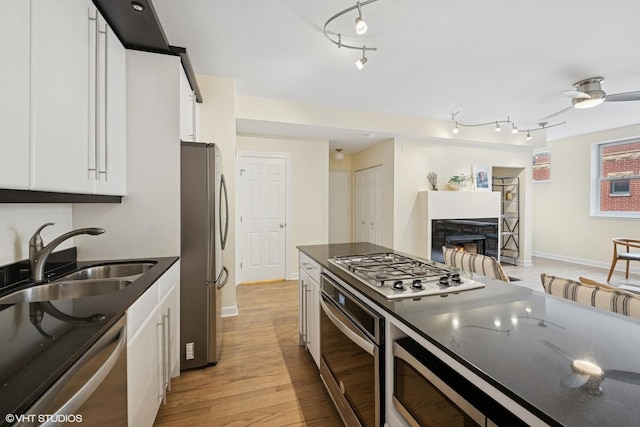 3721 N Sheffield Ave Unit B2, Chicago, IL 60613 - kitchen featuring appliances with stainless steel finishes, a sink, white cabinetry, and a warm lit fireplace