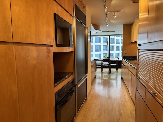 155 N Harbor Dr Unit 1103, Chicago, IL 60601 - kitchen with black appliances, modern cabinets, light wood finished floors, brown cabinetry, and dark stone countertops