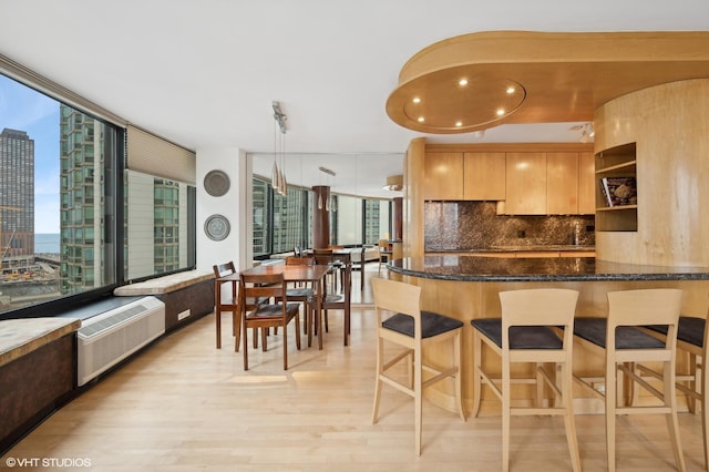 155 N Harbor Dr Unit 1103, Chicago, IL 60601 - kitchen featuring light wood-style flooring, a wall mounted air conditioner, dark stone countertops, backsplash, and a kitchen breakfast bar