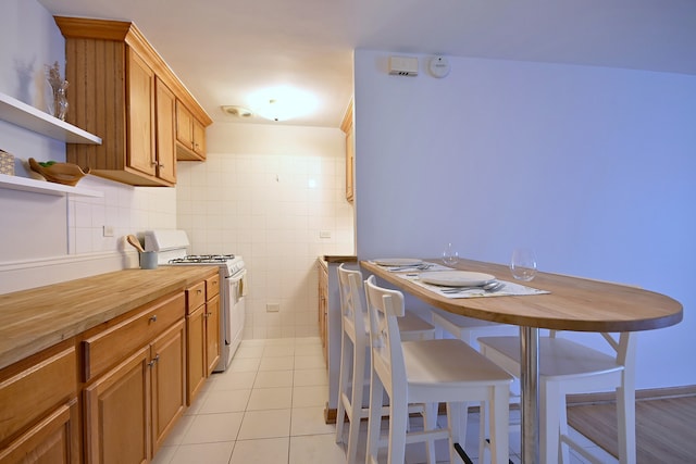 5816 N Nagle Ave Unit B, Chicago, IL 60646 - kitchen with white gas stove, butcher block countertops, light tile patterned floors, open shelves, and brown cabinetry