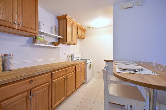 5816 N Nagle Ave Unit B, Chicago, IL 60646 - kitchen featuring white gas range oven, wooden counters, light tile patterned floors, open shelves, and tile walls