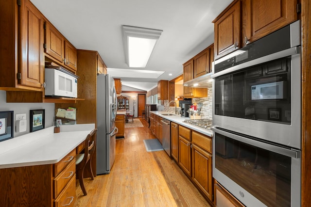 22W300 Arbor Ln, Glen Ellyn, IL 60137 - kitchen featuring stainless steel appliances, a sink, light wood finished floors, tasteful backsplash, and light countertops