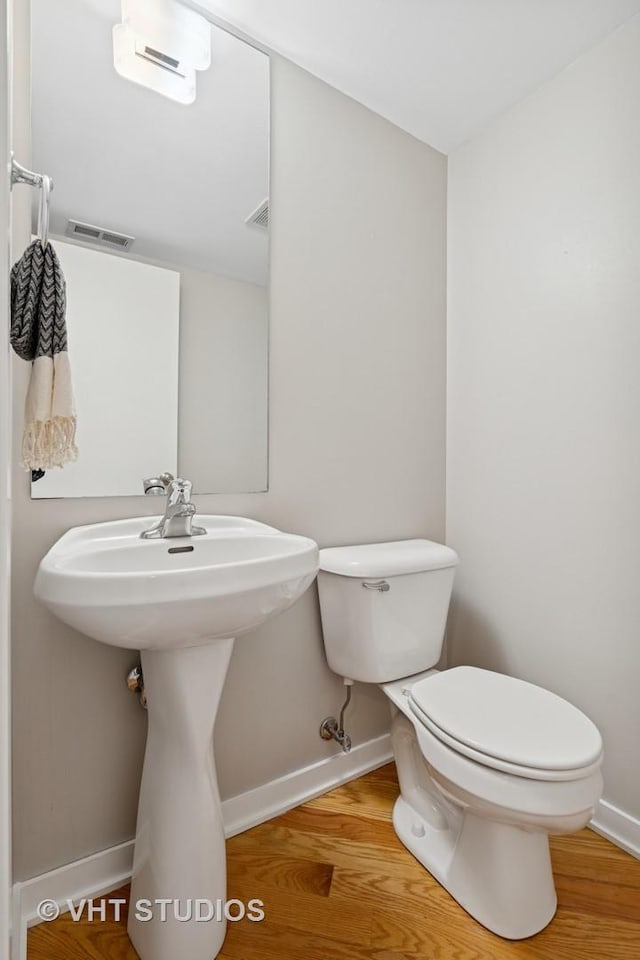 3201 N Ravenswood Ave Unit 203, Chicago, IL 60657 - half bathroom with baseboards, toilet, wood finished floors, a wall unit AC, and a sink