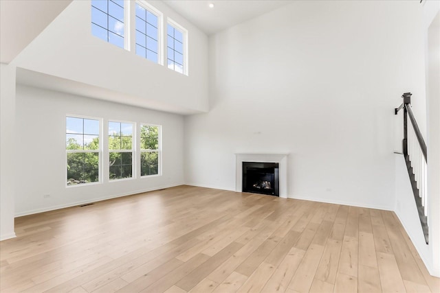 28 Open Pkwy, Hawthorn Woods, IL 60047 - unfurnished living room with a fireplace, light wood-style flooring, baseboards, a high ceiling, and stairs