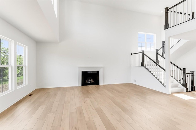 28 Open Pkwy, Hawthorn Woods, IL 60047 - unfurnished living room featuring a high ceiling, light wood-style flooring, a fireplace, stairs, and baseboards