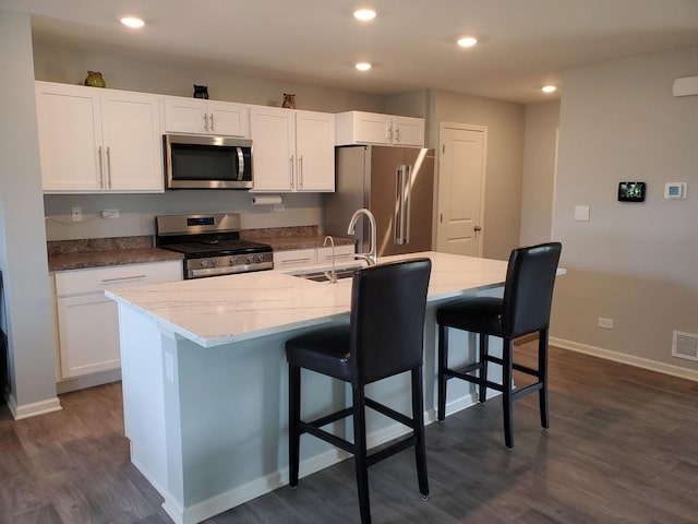 754 Westbury Dr, Cary, IL 60013 - kitchen featuring stainless steel appliances, white cabinets, dark wood-type flooring, a center island with sink, and light stone countertops