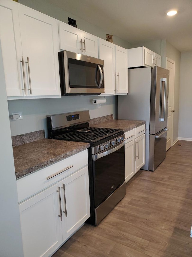 754 Westbury Dr, Cary, IL 60013 - kitchen featuring stainless steel appliances, dark countertops, white cabinets, light wood finished floors, and recessed lighting