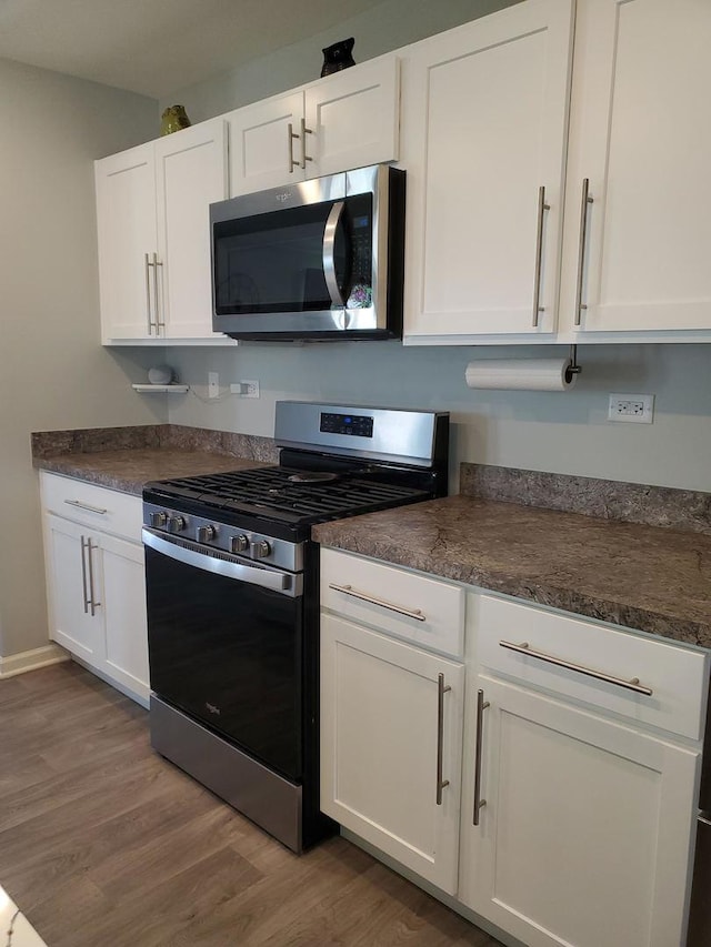 754 Westbury Dr, Cary, IL 60013 - kitchen with stainless steel appliances, light wood-style floors, white cabinets, and dark countertops