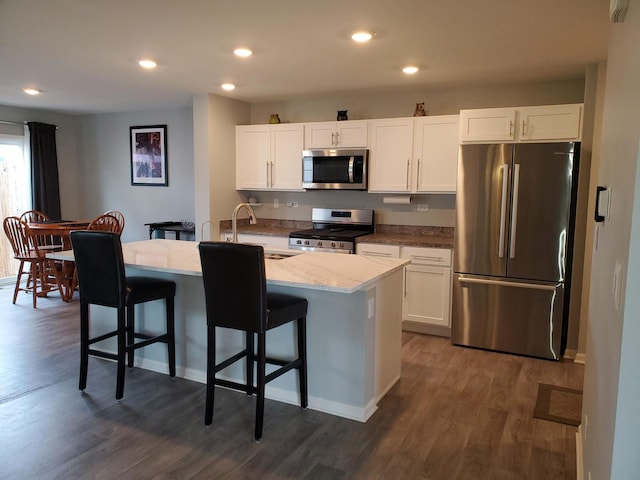 754 Westbury Dr, Cary, IL 60013 - kitchen featuring appliances with stainless steel finishes, dark wood finished floors, light stone counters, recessed lighting, and a breakfast bar area