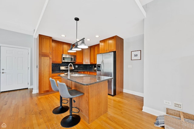 4606 S Lake Park Ave Unit 201N, Chicago, IL 60653 - kitchen featuring appliances with stainless steel finishes, baseboards, a sink, light wood-style floors, and a kitchen island with sink