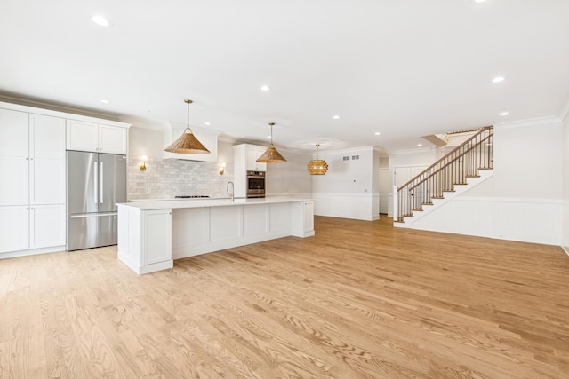 6202 Flagg Creek Ln, Western Springs, IL 60558 - kitchen with stainless steel appliances, light countertops, white cabinetry, ornamental molding, and light wood-style flooring