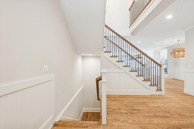 6202 Flagg Creek Ln, Western Springs, IL 60558 - staircase featuring wood finished floors, a decorative wall, a chandelier, wainscoting, and a towering ceiling