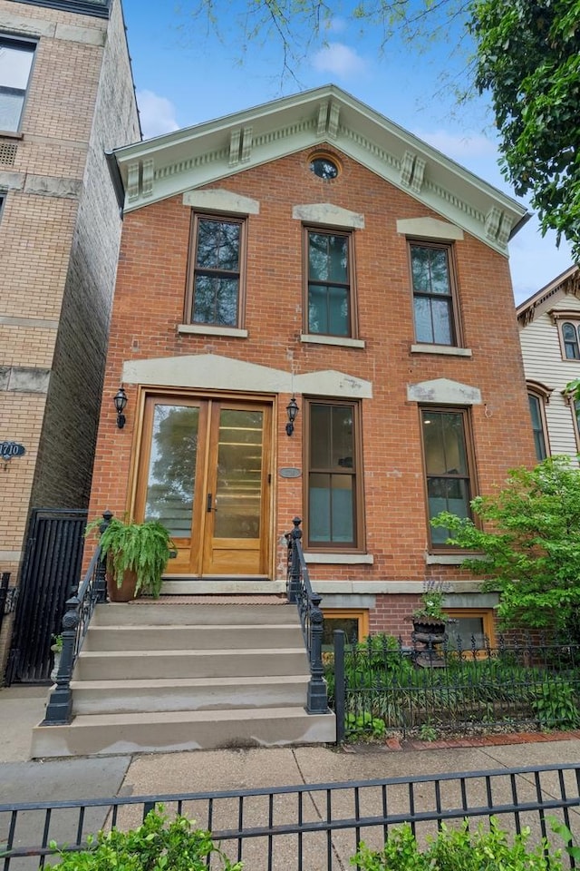 view of front of house with brick siding, a fenced front yard, and entry steps