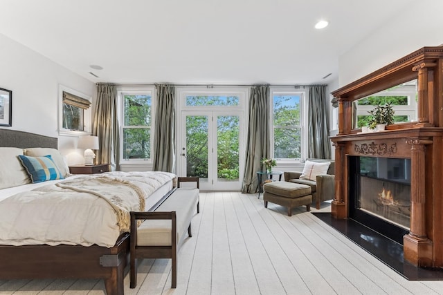 bedroom featuring a glass covered fireplace, light wood finished floors, access to outside, and recessed lighting