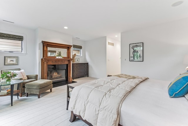 bedroom featuring recessed lighting, a fireplace with flush hearth, and light wood-type flooring