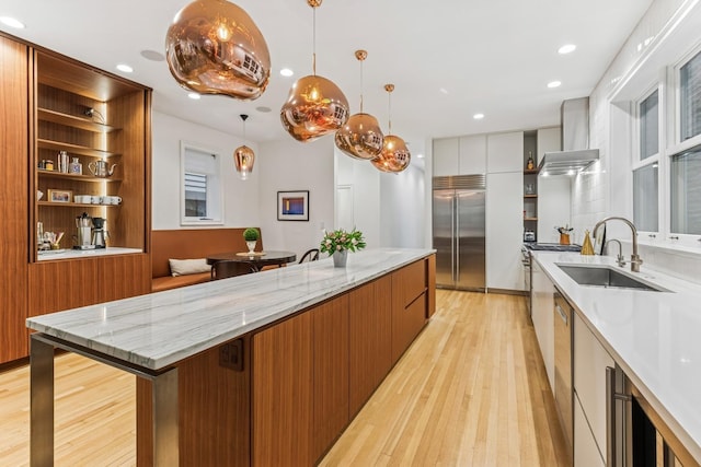 kitchen featuring appliances with stainless steel finishes, open shelves, wall chimney exhaust hood, modern cabinets, and light wood-style flooring
