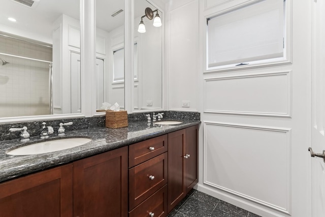 full bath with double vanity, tiled shower, and tile patterned flooring