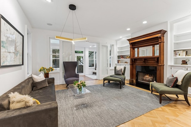 living area featuring a fireplace with flush hearth, recessed lighting, and built in shelves