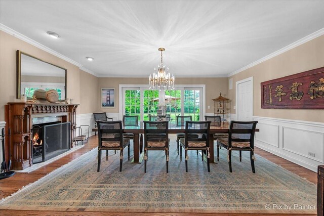 3 Woodley Mnr, Winnetka, IL 60093 - dining room with crown molding, wood finished floors, a chandelier, a warm lit fireplace, and wainscoting