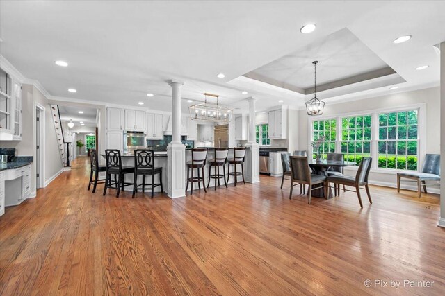 3 Woodley Mnr, Winnetka, IL 60093 - dining room featuring ornate columns, recessed lighting, light wood finished floors, crown molding, and a tray ceiling
