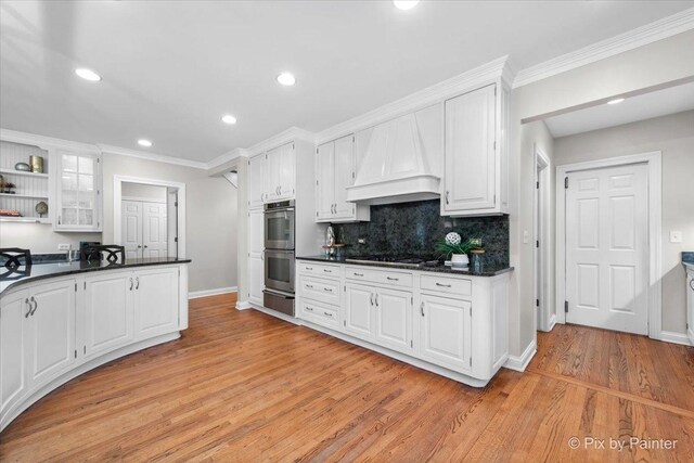 3 Woodley Mnr, Winnetka, IL 60093 - kitchen featuring a warming drawer, dark countertops, custom range hood, light wood finished floors, and white cabinetry