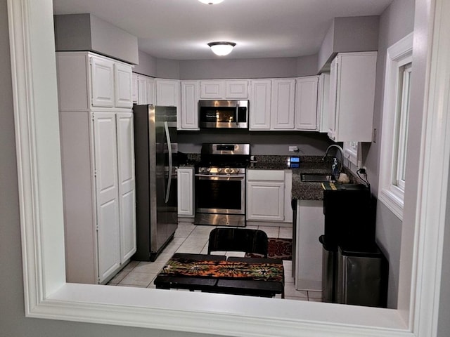 1602 Nightengale Cir, Lindenhurst, IL 60046 - kitchen featuring stainless steel appliances, a sink, white cabinetry, light tile patterned floors, and dark stone counters