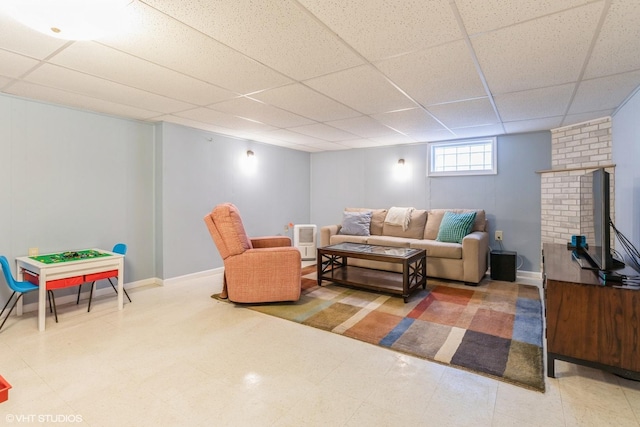 living room with a paneled ceiling, tile patterned floors, and baseboards