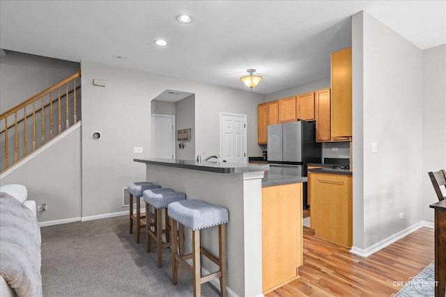616 Springbrook Trl N, Oswego, IL 60543 - kitchen with a kitchen breakfast bar, dark countertops, baseboards, recessed lighting, and light wood-type flooring