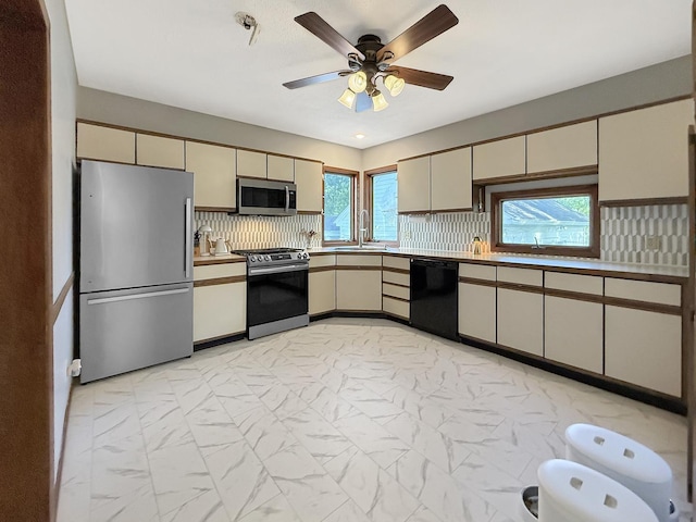 1351 W Stover St, Freeport, IL 61032 - kitchen with appliances with stainless steel finishes, a sink, light marble finish floors, cream cabinets, and healthy amount of natural light