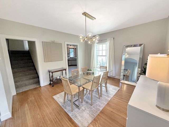 1351 W Stover St, Freeport, IL 61032 - dining space with light wood-style flooring, stairs, a chandelier, arched walkways, and baseboards