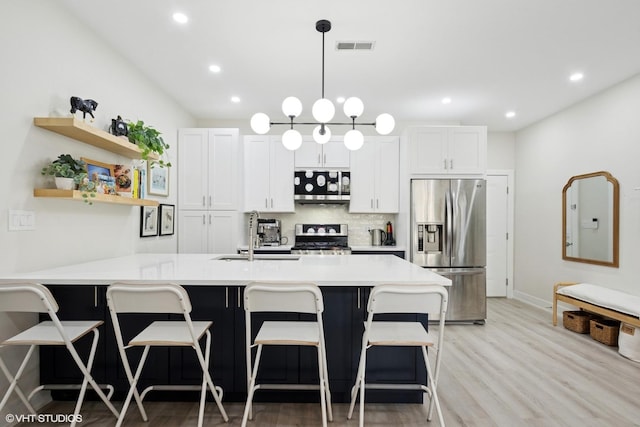 4150 N Kenmore Ave Unit 206, Chicago, IL 60613 - kitchen featuring stainless steel appliances, a sink, light countertops, light wood-style flooring, and a kitchen breakfast bar
