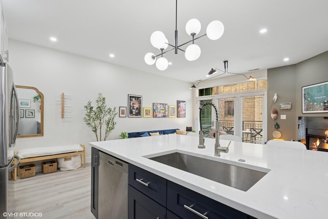 4150 N Kenmore Ave Unit 206, Chicago, IL 60613 - kitchen featuring appliances with stainless steel finishes, a sink, open floor plan, light wood-type flooring, and light stone counters