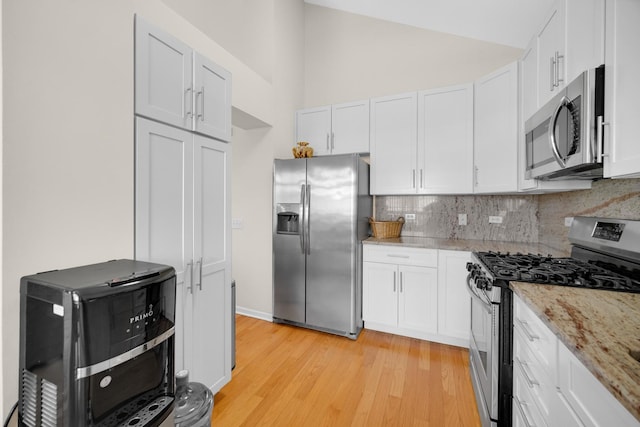 679 Prestwick Ln, Wheeling, IL 60090 - kitchen featuring appliances with stainless steel finishes, backsplash, light wood finished floors, white cabinetry, and light stone countertops