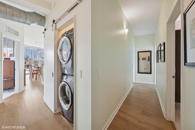 1200 W Monroe St Unit 808, Chicago, IL 60607 - washroom with stacked washer / dryer, light wood finished floors, a barn door, and baseboards