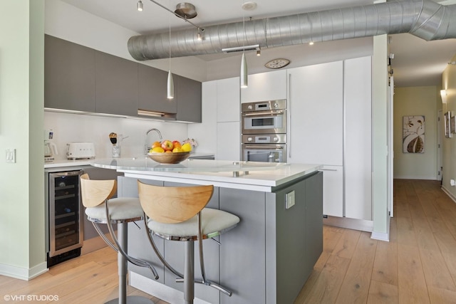 1200 W Monroe St Unit 808, Chicago, IL 60607 - kitchen with beverage cooler, a kitchen bar, modern cabinets, light wood-style floors, and light countertops