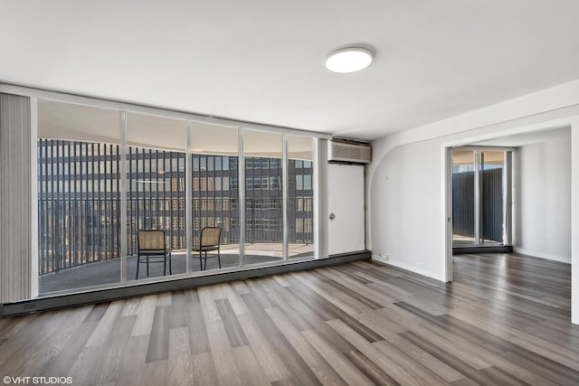 300 N State St Unit 4930, Chicago, IL 60654 - empty room with wood finished floors, an AC wall unit, floor to ceiling windows, and baseboards