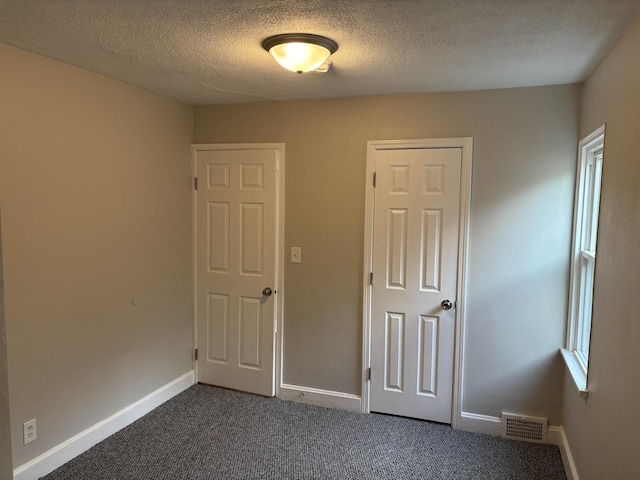 926 Park Ave, Winthrop Harbor, IL 60096 - unfurnished bedroom featuring baseboards, a textured ceiling, and dark colored carpet