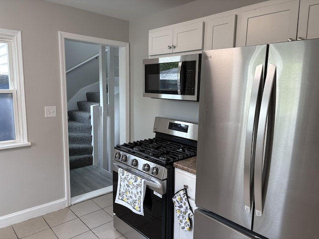 926 Park Ave, Winthrop Harbor, IL 60096 - kitchen featuring appliances with stainless steel finishes, light tile patterned floors, white cabinetry, dark countertops, and baseboards