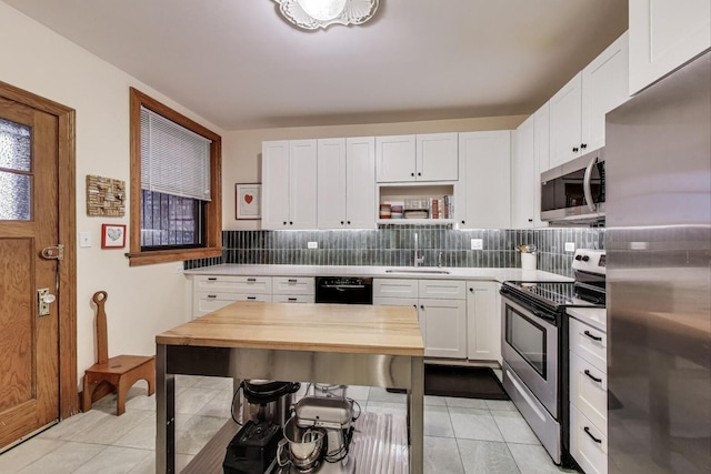 5143 S Greenwood Ave Unit 1, Chicago, IL 60615 - kitchen with appliances with stainless steel finishes, backsplash, white cabinets, light tile patterned floors, and wood counters
