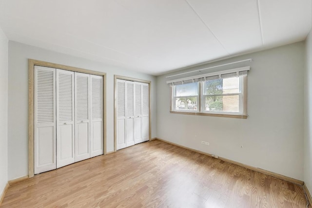6478 N NW Hwy Unit 1, Chicago, IL 60631 - unfurnished bedroom featuring multiple closets, light wood-style flooring, and baseboards