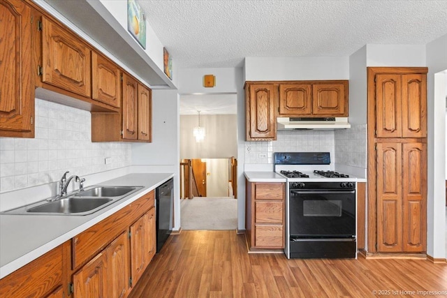 15435 Orogrande Dr, Oak Forest, IL 60452 - kitchen with under cabinet range hood, gas range oven, a sink, wood finished floors, and brown cabinetry