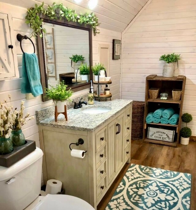 310 N Oak Ln, Dixon, IL 61021 - half bath featuring toilet, wood finished floors, lofted ceiling, vanity, and wood walls