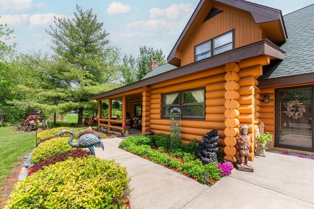 310 N Oak Ln, Dixon, IL 61021 - view of home's exterior with log siding, a shingled roof, and a chimney